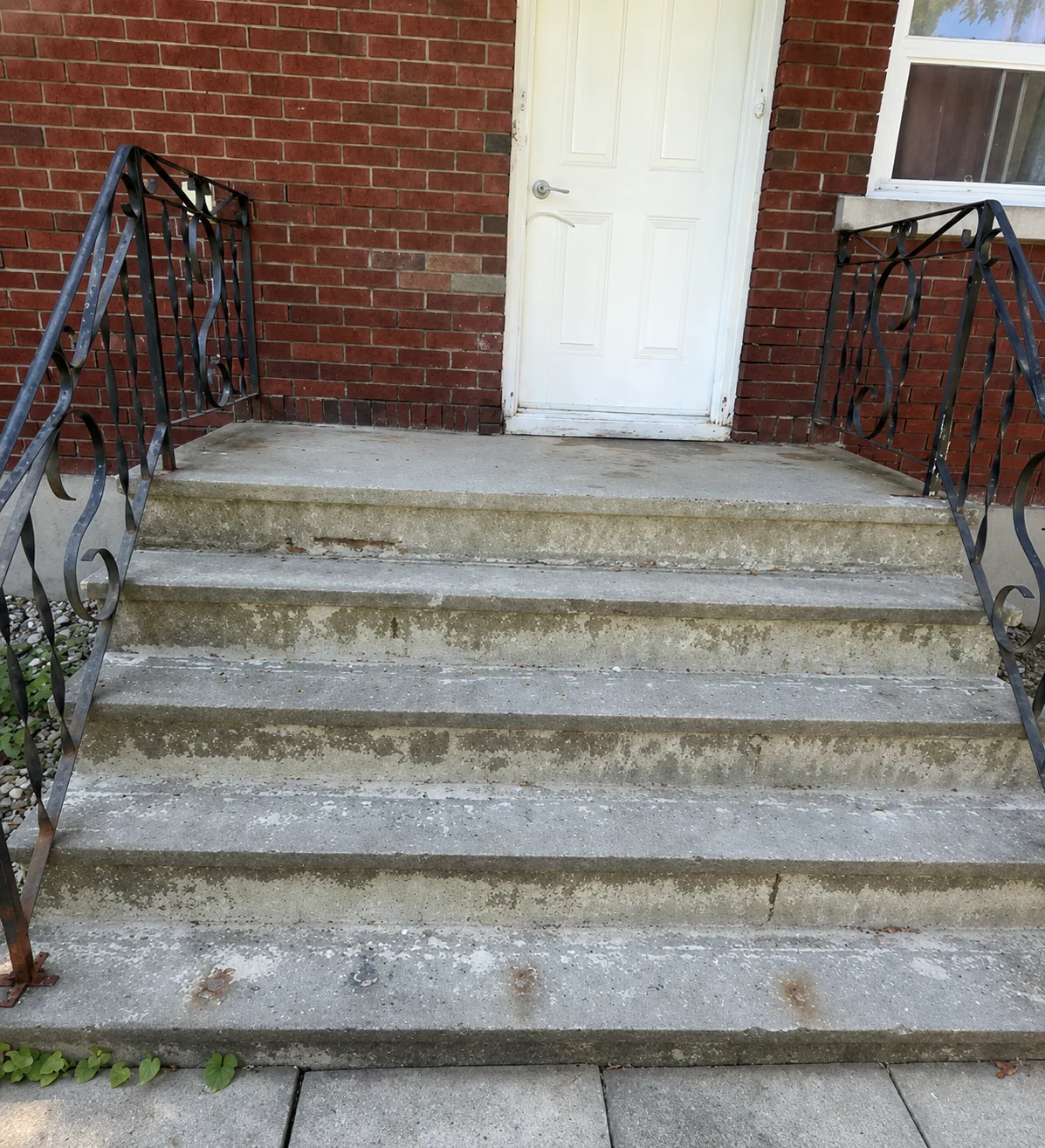 Worn concrete front steps before parging in Orléans
